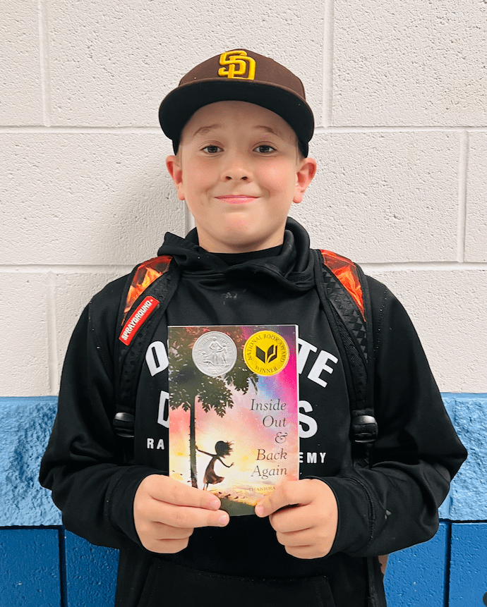 student holding a book received for earning a  praise award